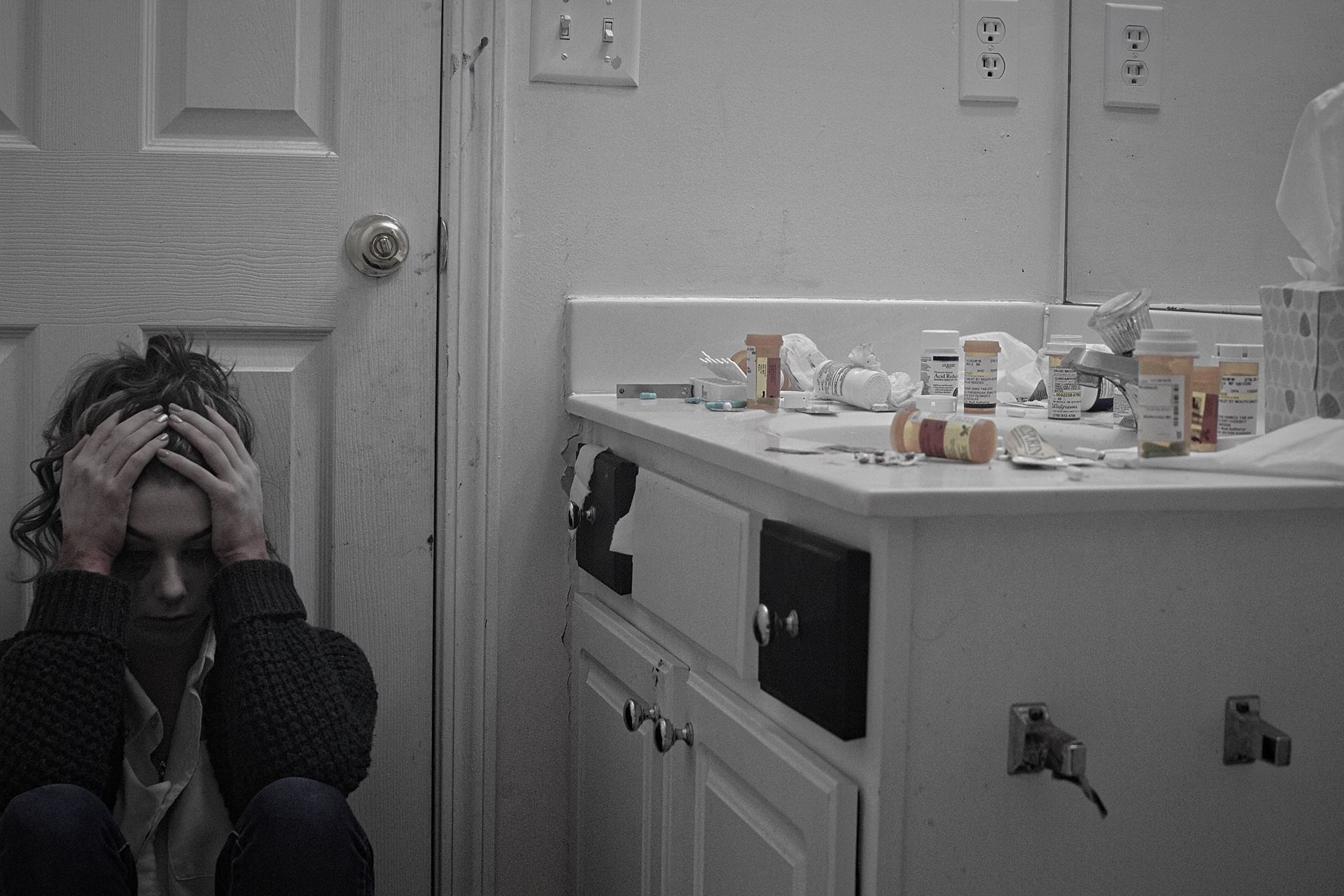 a person sat on the floor next to cabinet with medication